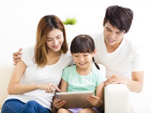 happy family and daughter using tablet on sofa
